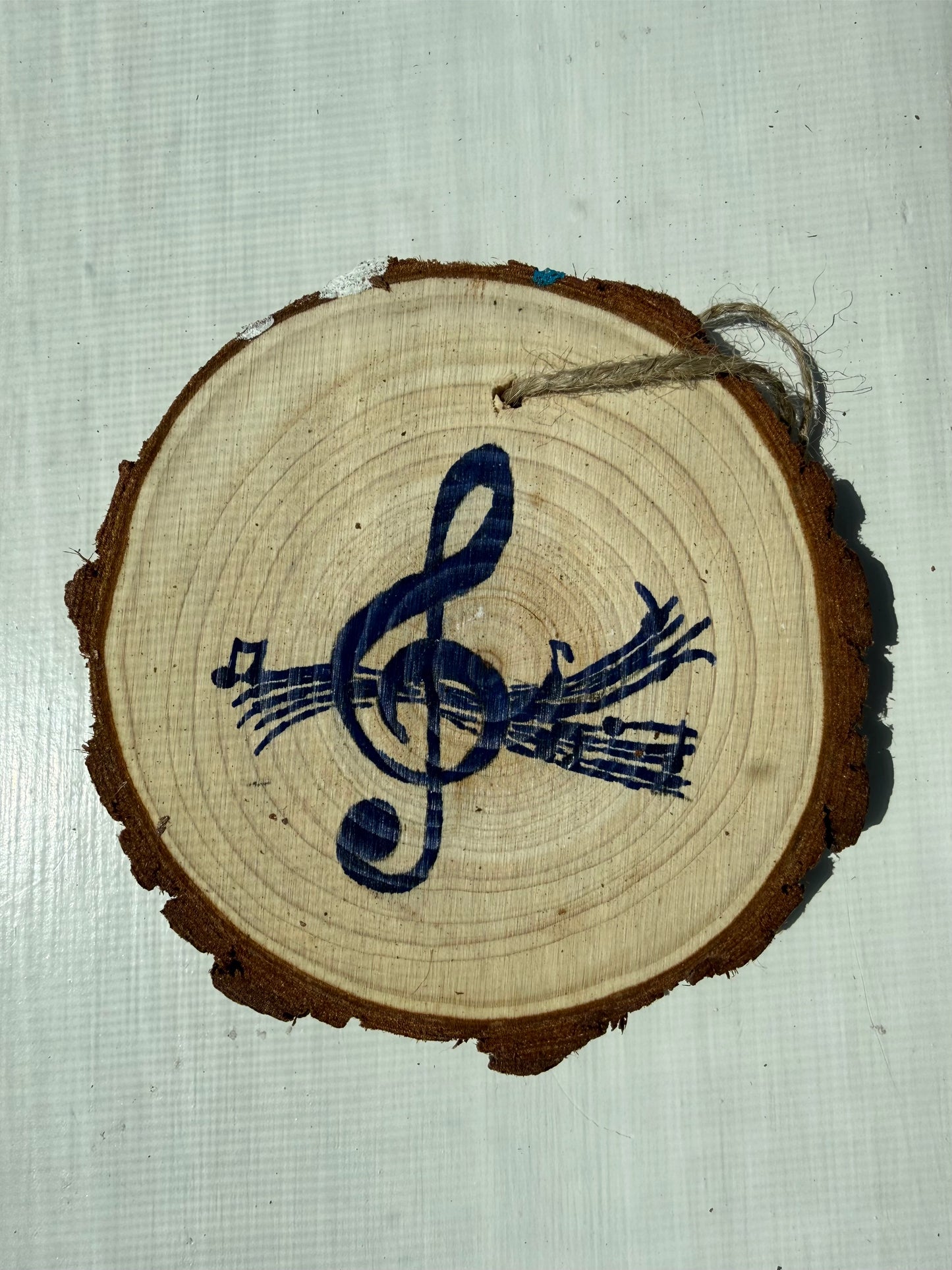 Wooden ornament with a blue music note design on a textured white background