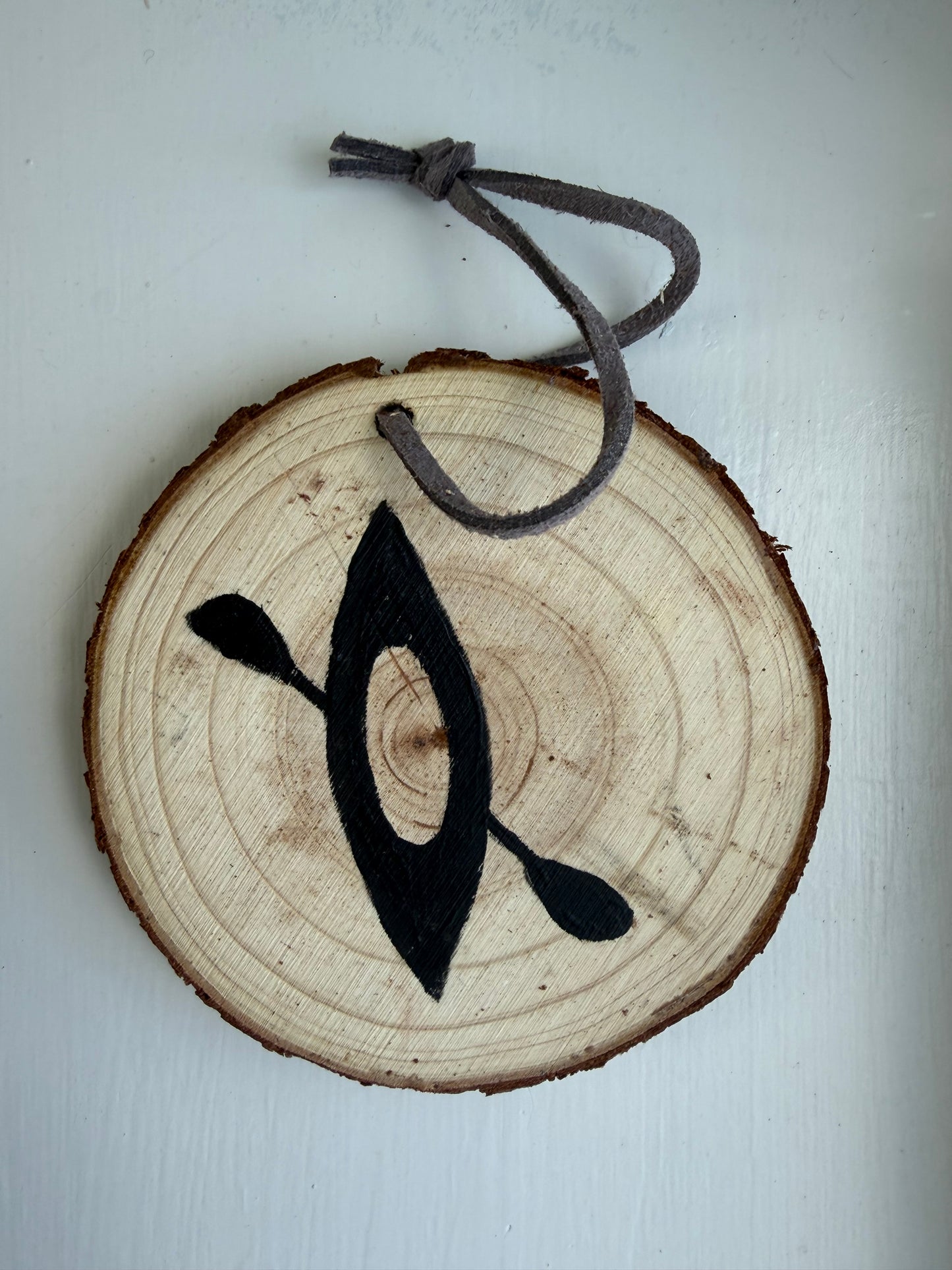 Wooden ornament with a painted black kayak design on it
