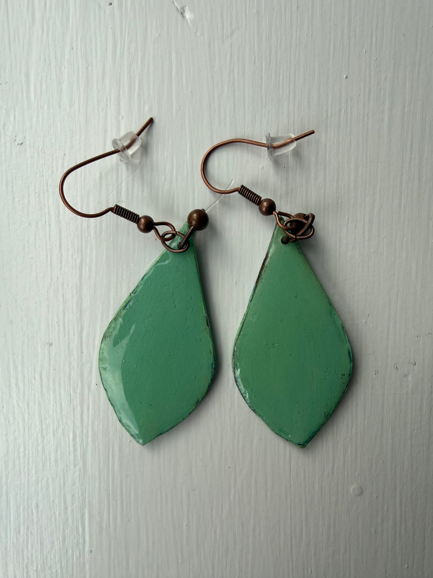 Teardrop-shaped earrings with teal background on each one