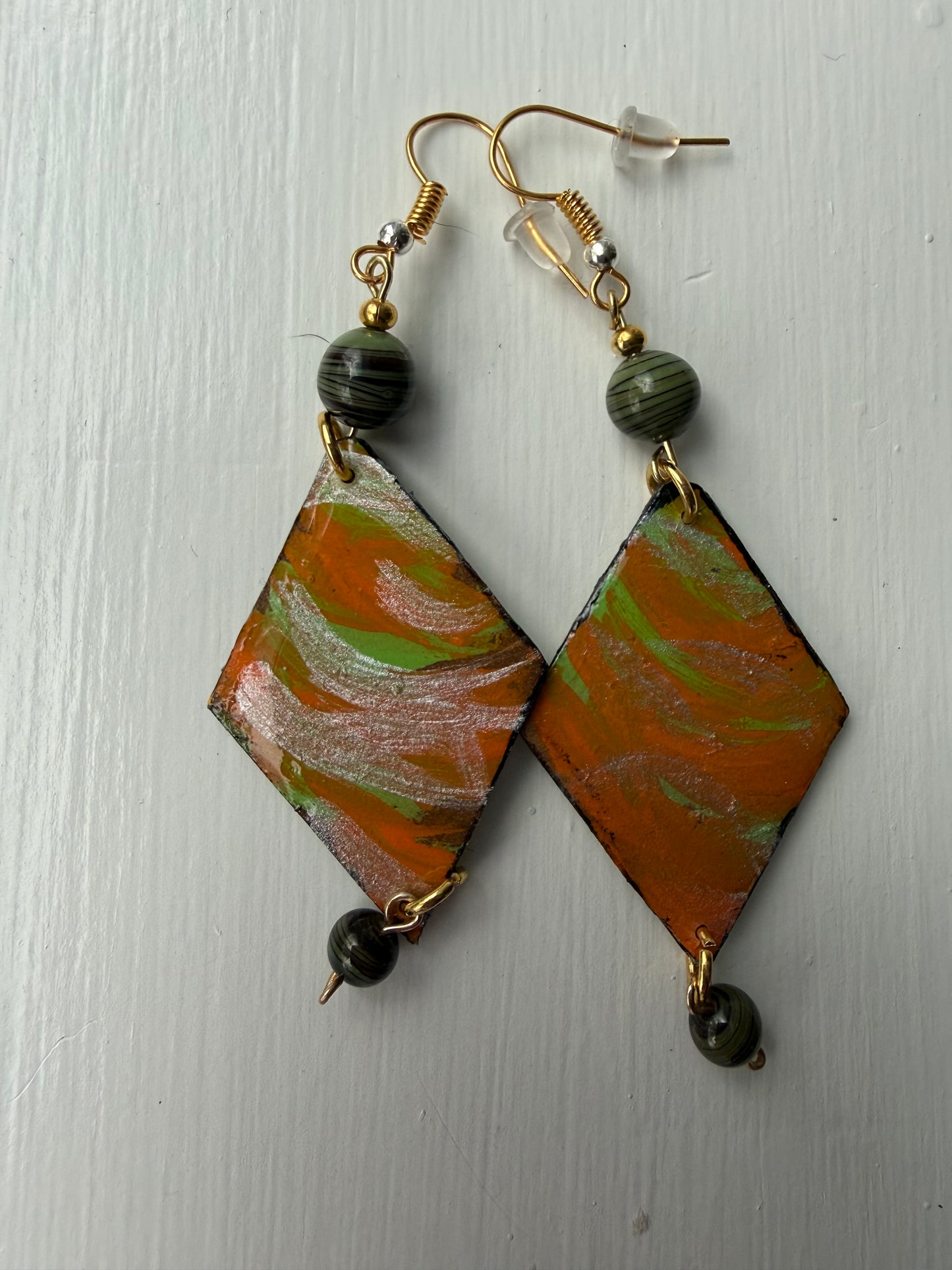 Pair of earrings with green, orange and silver design on each one