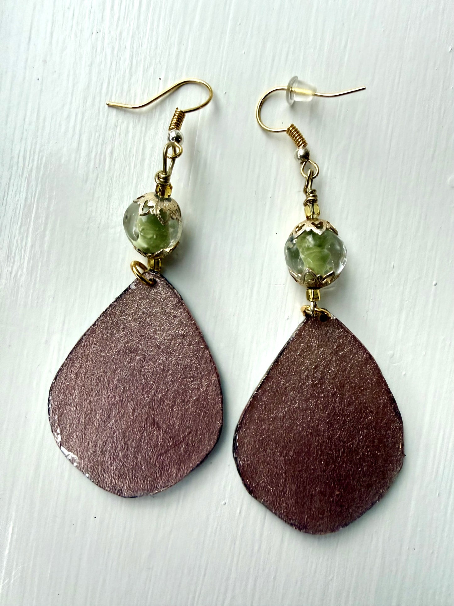 Bronze teardrop-shaped earrings on a light wooden surface