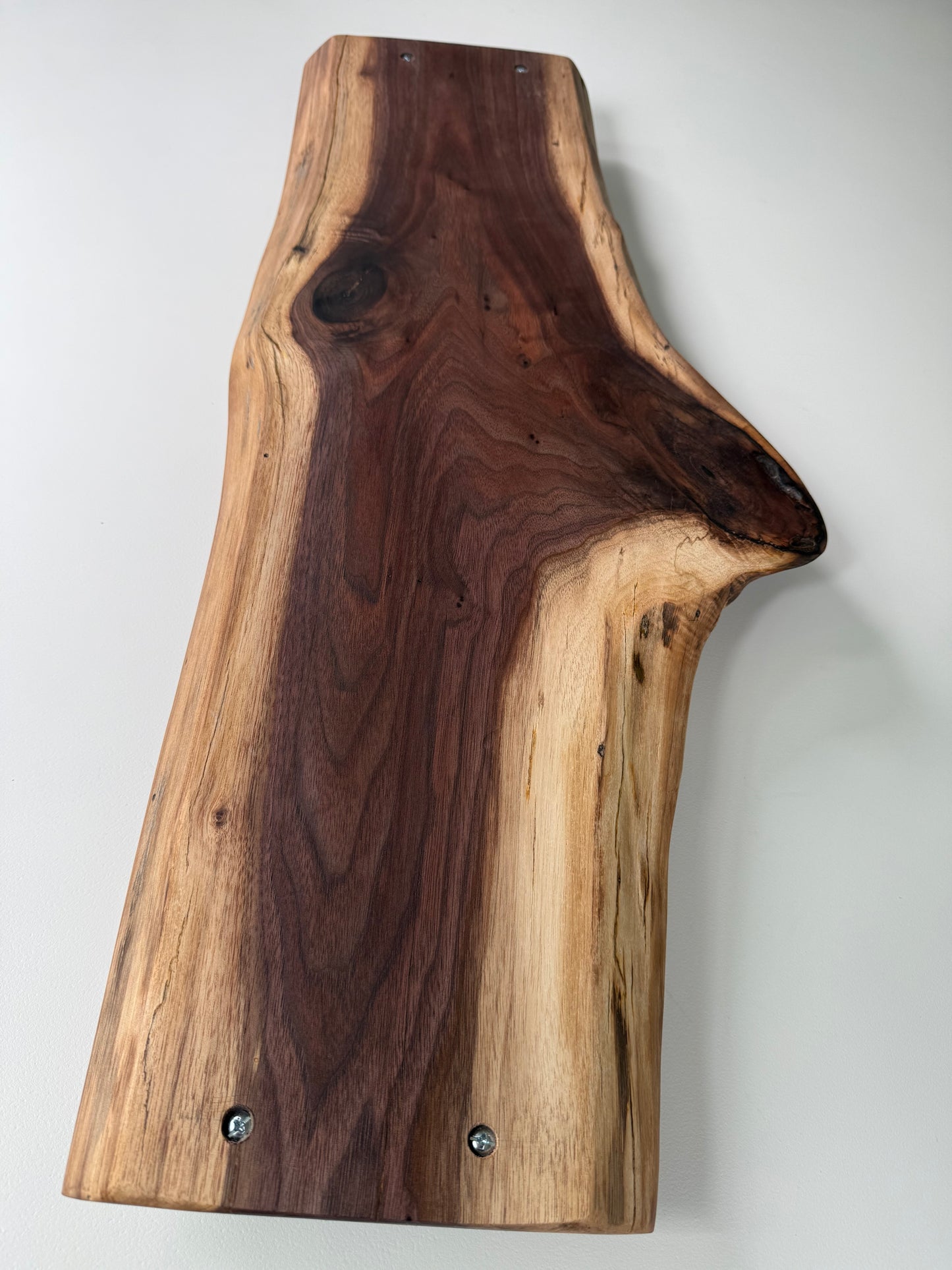 Wooden charcuterie board with a natural edge on a white background