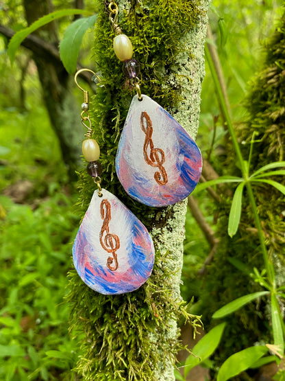 Pair of earrings with musical note design on a mossy branch
