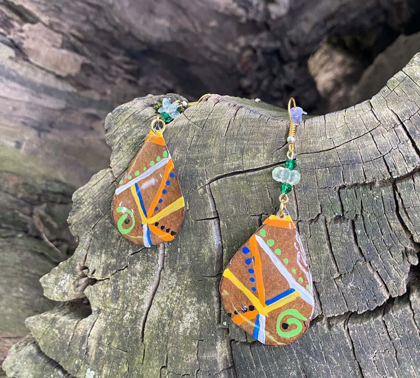 Decorative earrings with colorful patterns on a tree log