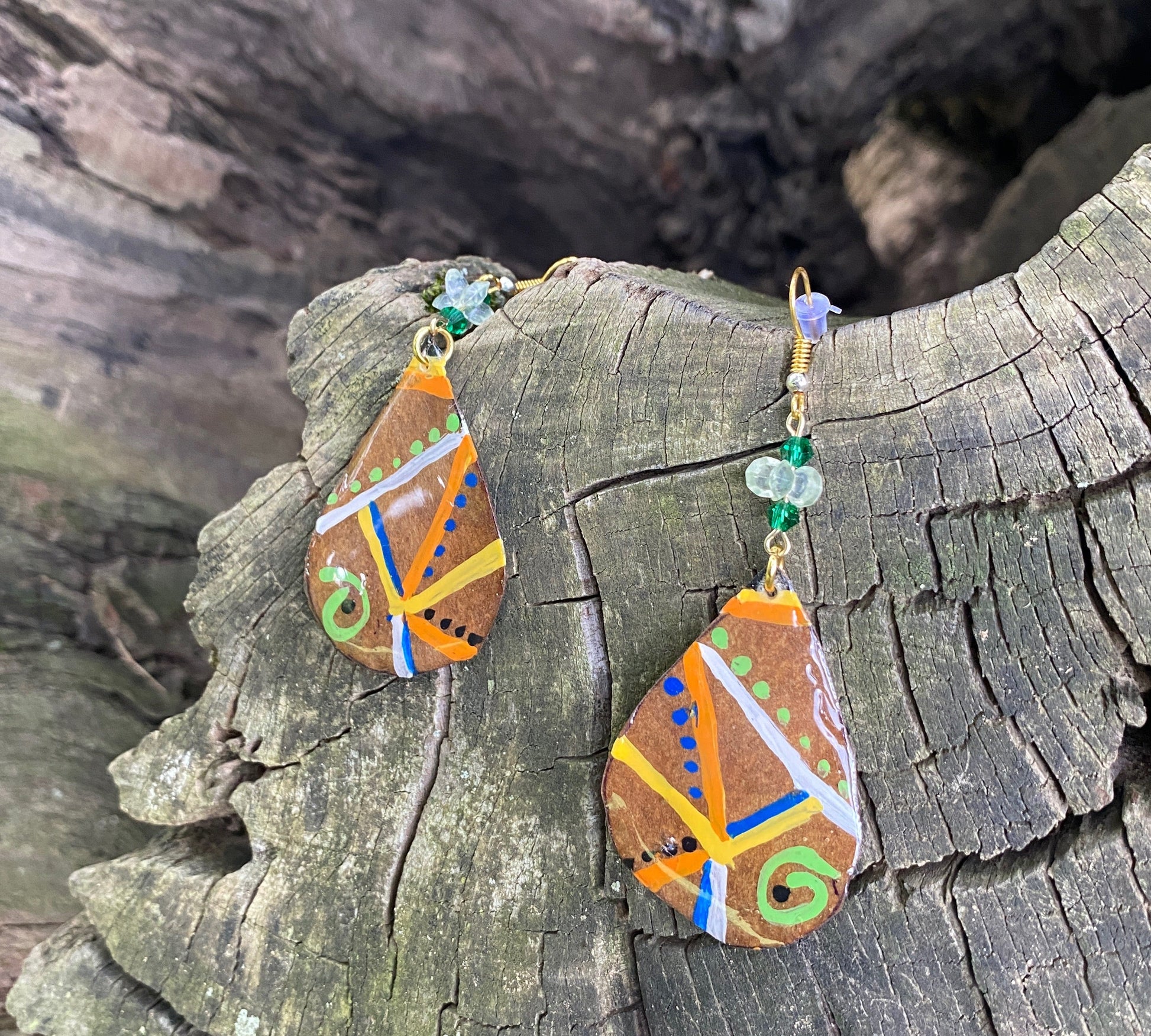 Decorative earrings with colorful patterns on a tree log