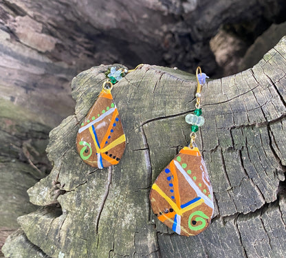 Decorative earrings with colorful patterns on a tree log