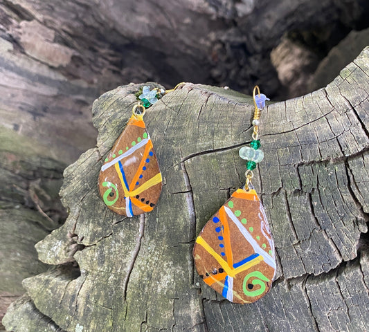 Decorative earrings with colorful patterns on a tree log