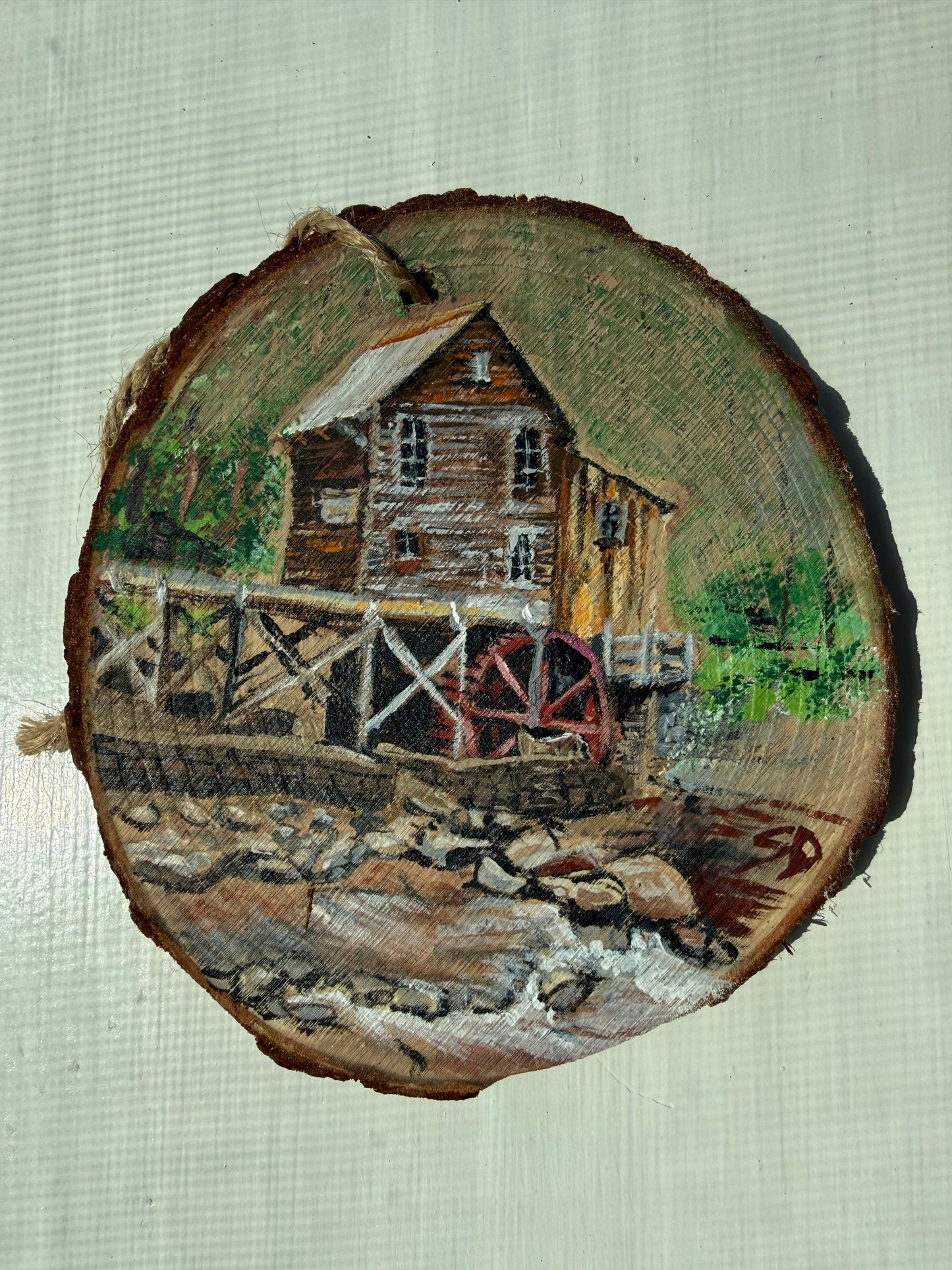 Wooden ornament with a painted scene of a mill