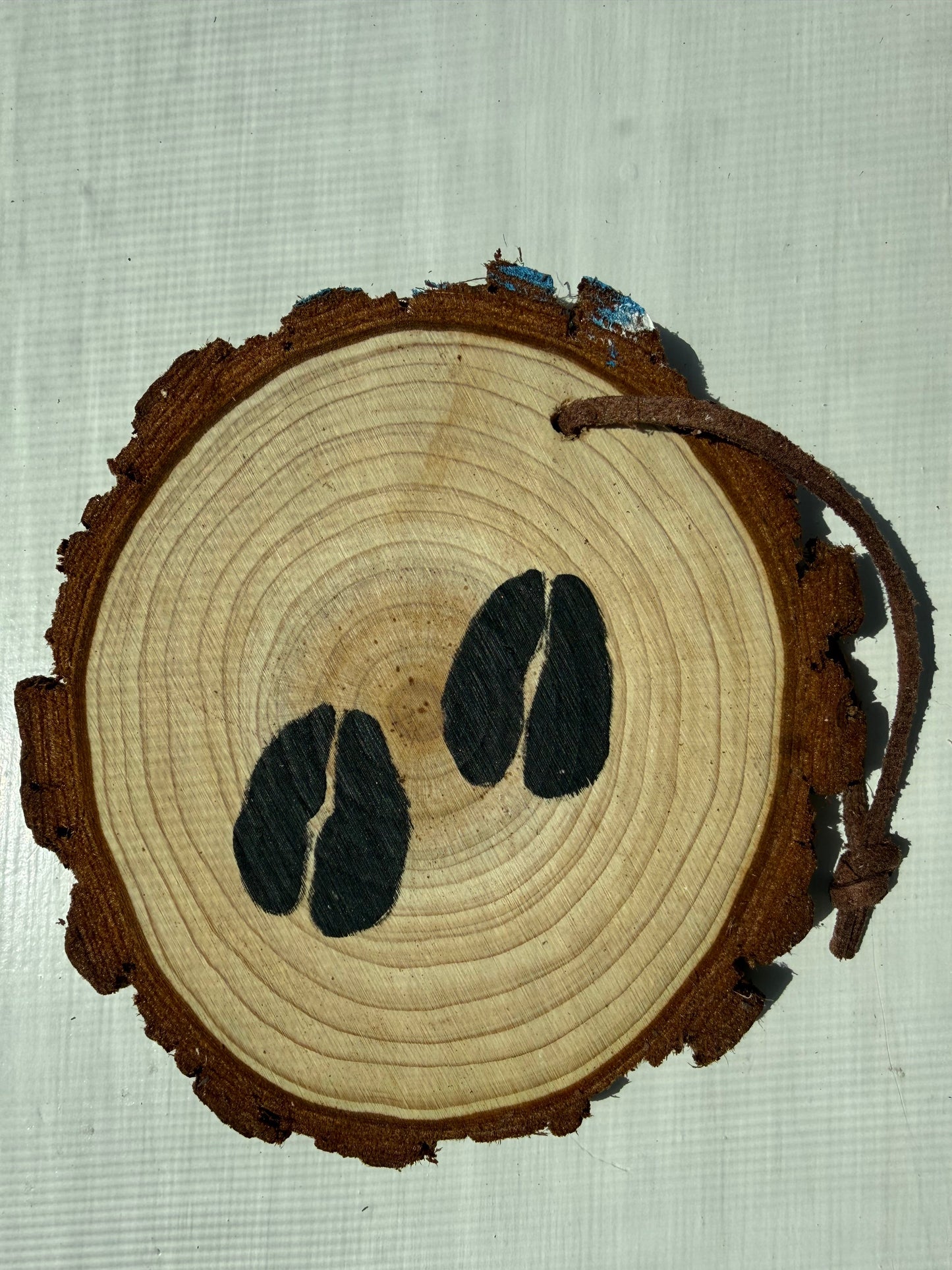 Wooden ornament with a painted design of black elk tracks