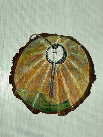 Wooden ornament with a painted banjo design on a textured white background