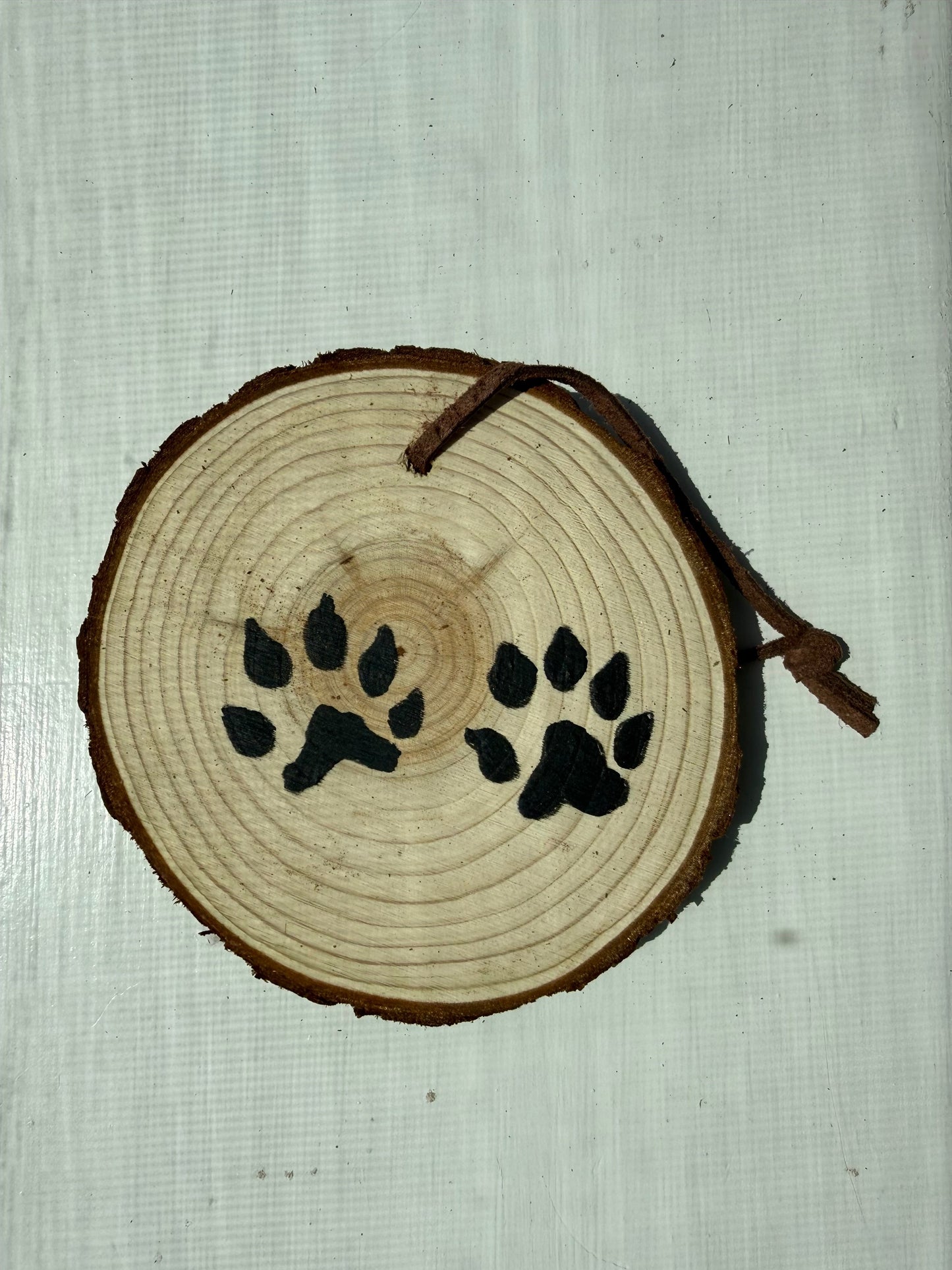Wooden ornament featuring hand-painted black bobcat tracks