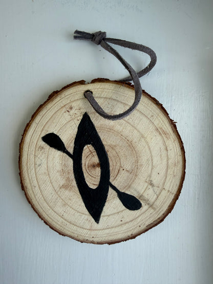 Wooden ornament with a painted black kayak design on it 