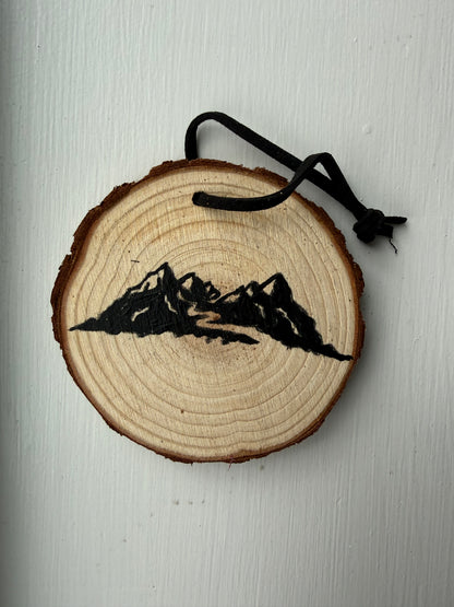 Wooden ornament with a painted mountain design on it