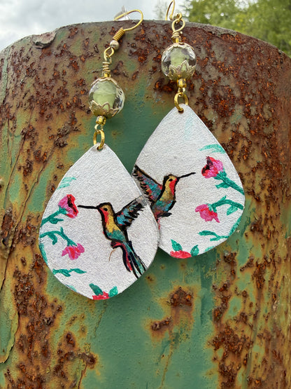 Pair of earrings with hummingbird design on a textured surface