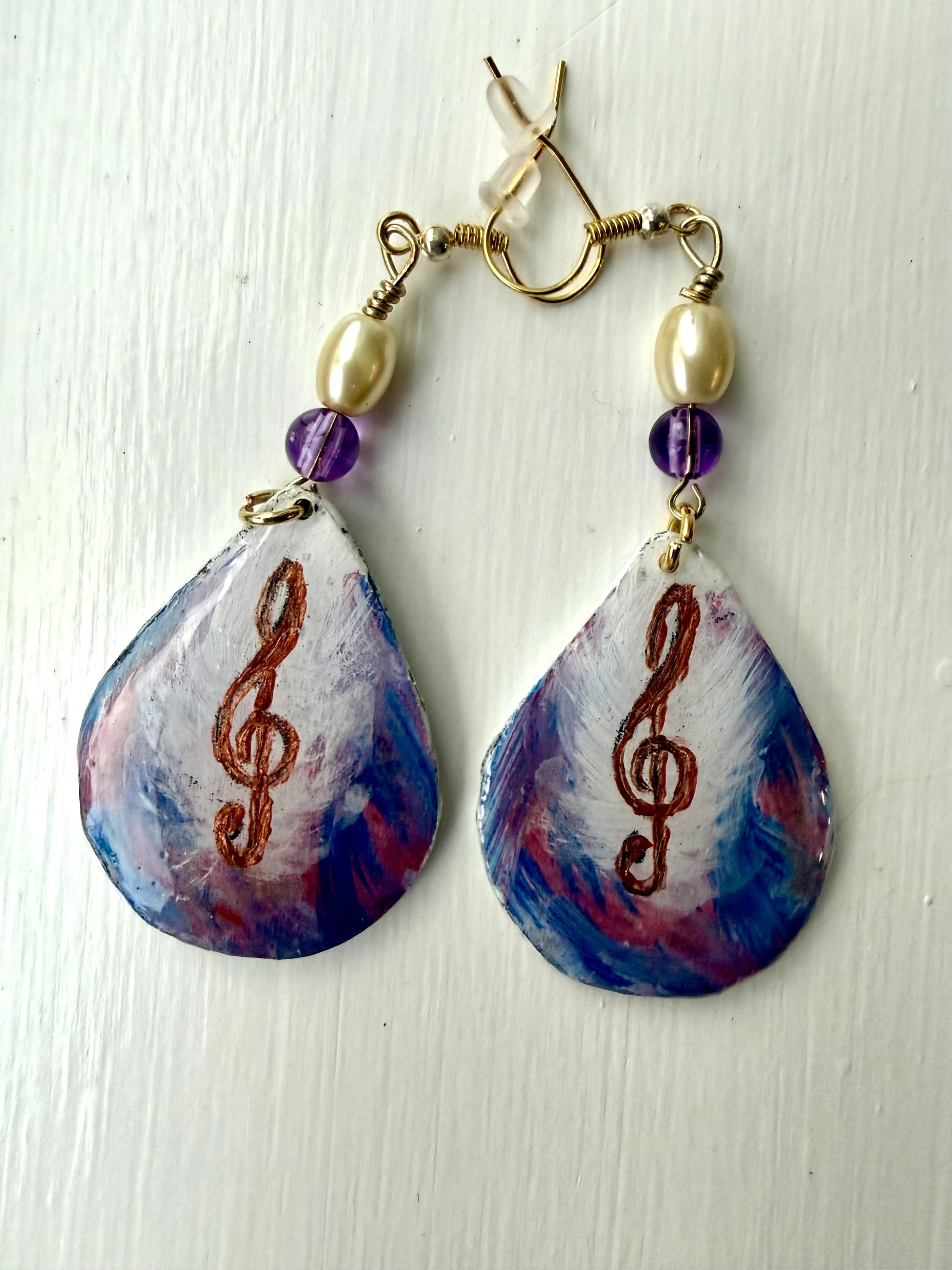 Teardrop-shaped earrings with musical note design on a white background