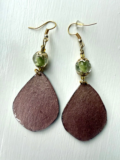 Bronze teardrop-shaped earrings on a light wooden surface