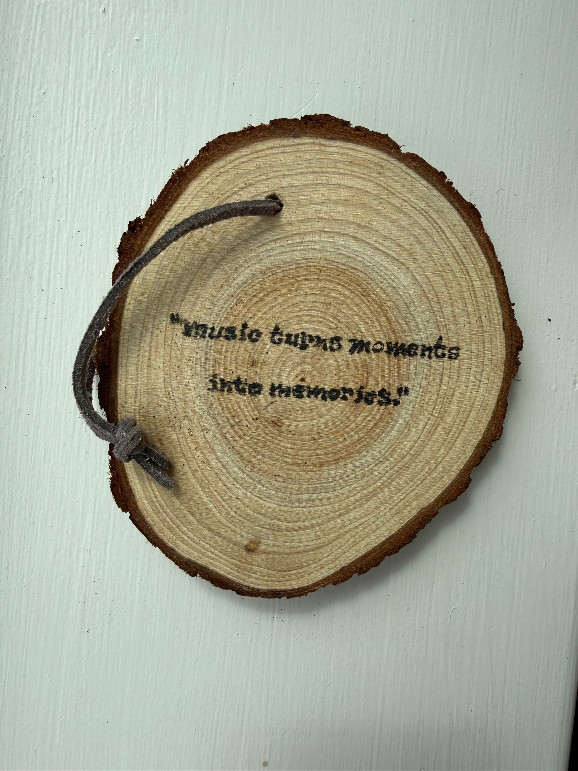 Wooden ornament that says "Music turns moments into memories."