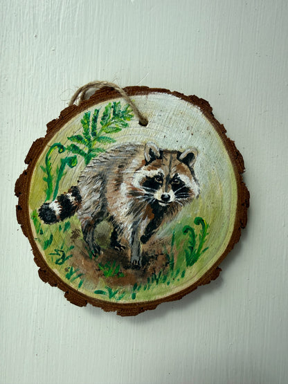 Wooden ornament with a painted raccoon design on it