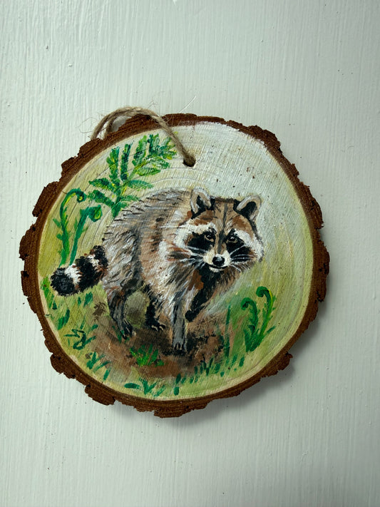 Wooden ornament with a painted raccoon design on it