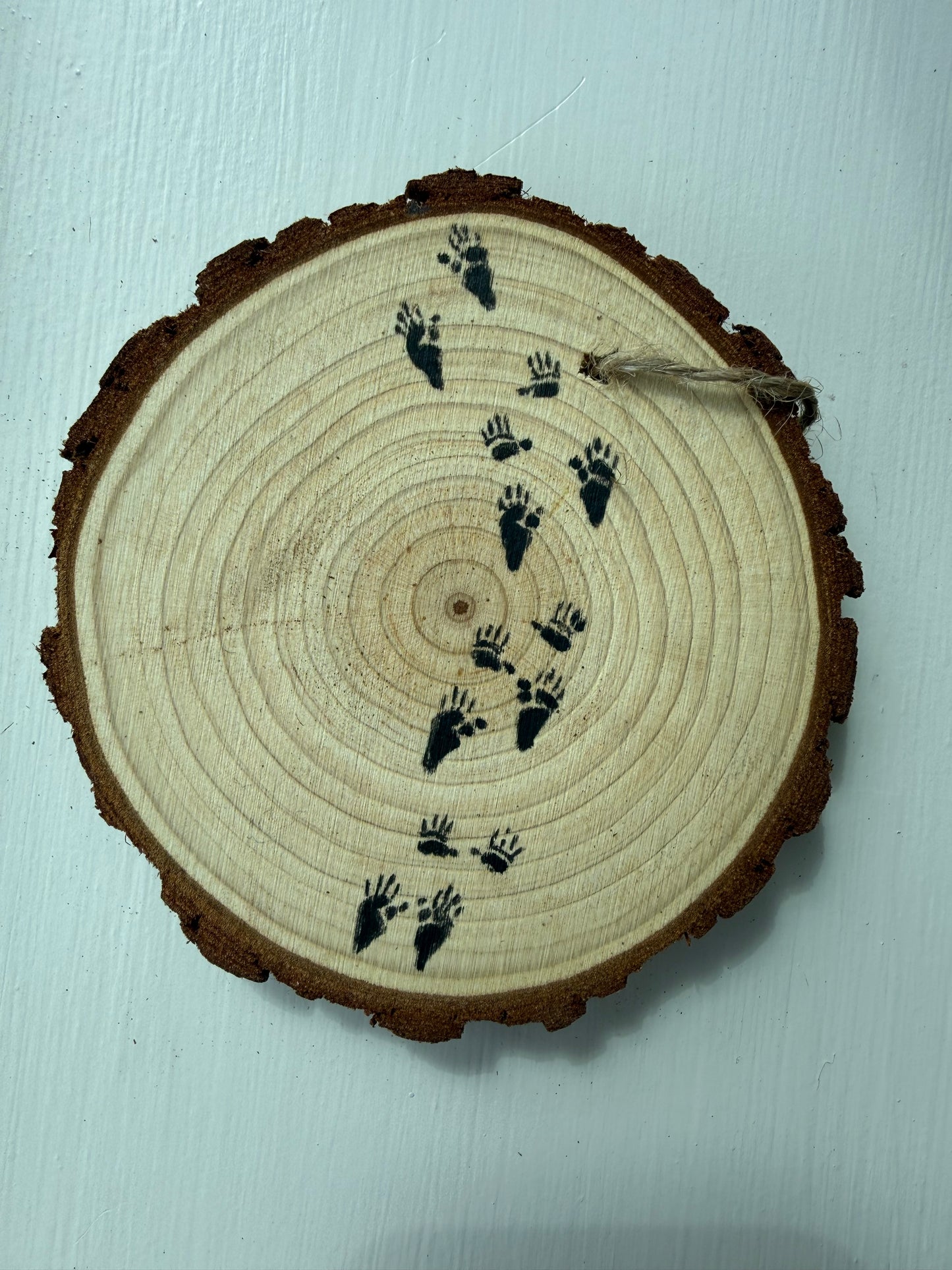 Wooden ornament with painted raccoon tracks on it