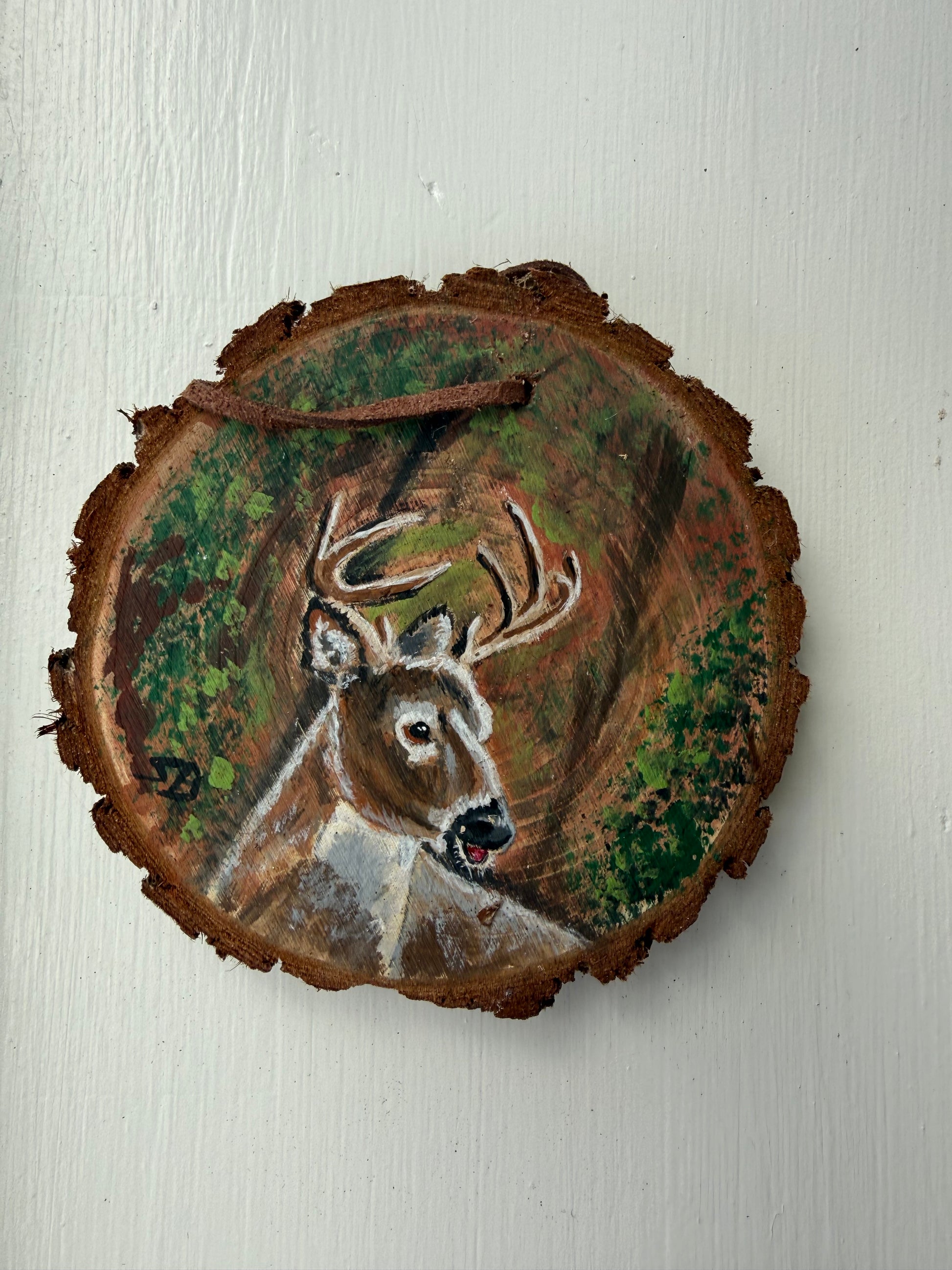 Wooden ornament with a painted deer design on it