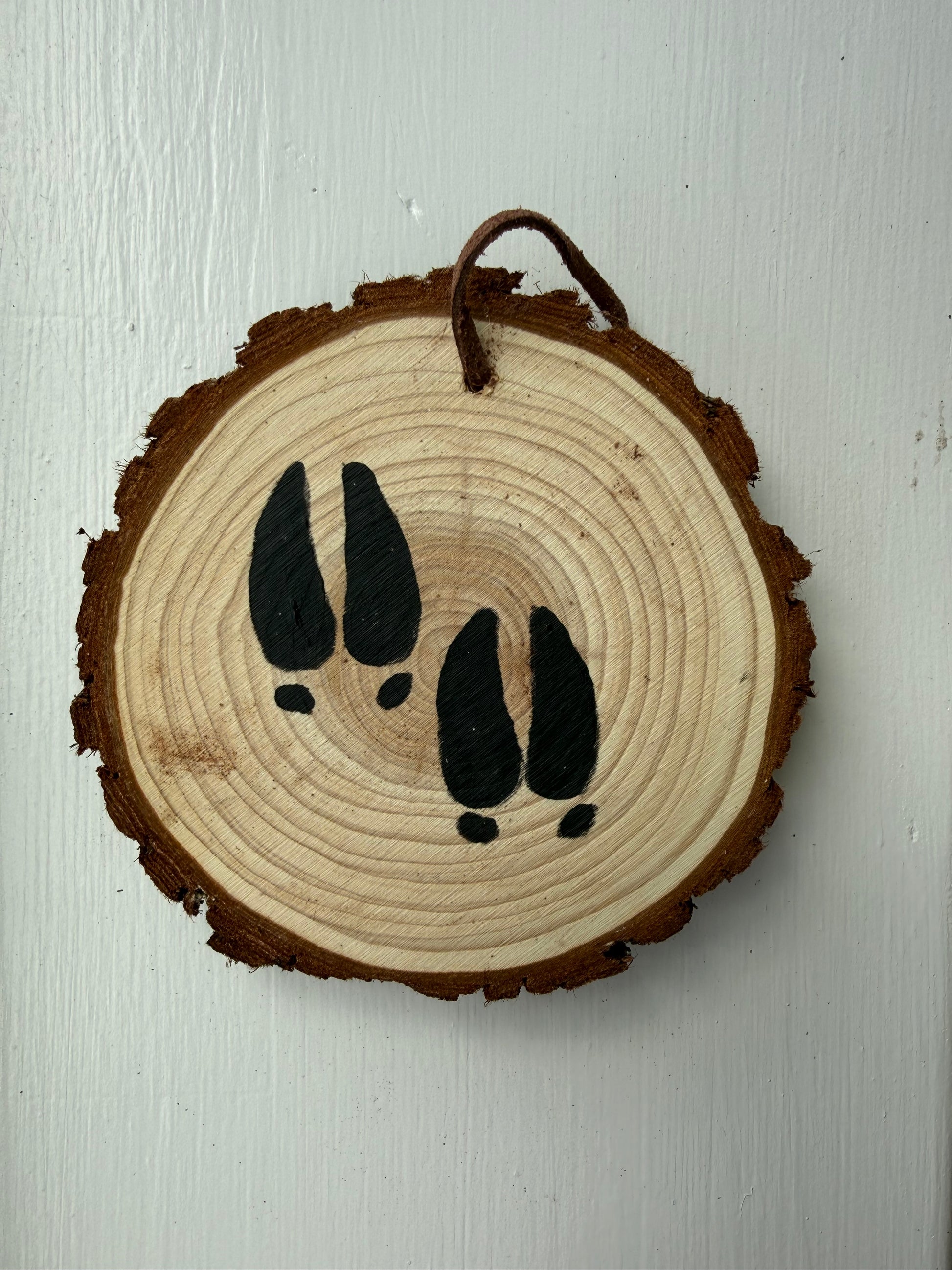 Wooden ornament with painted deer footprints on it