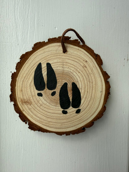 Wooden ornament with painted deer footprints on it