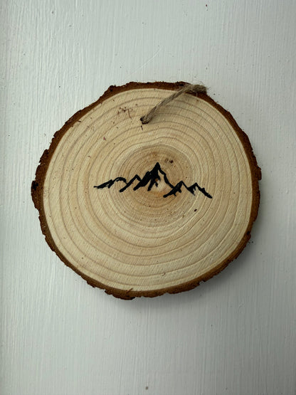 Wooden ornament with painted black mountain range on a white background