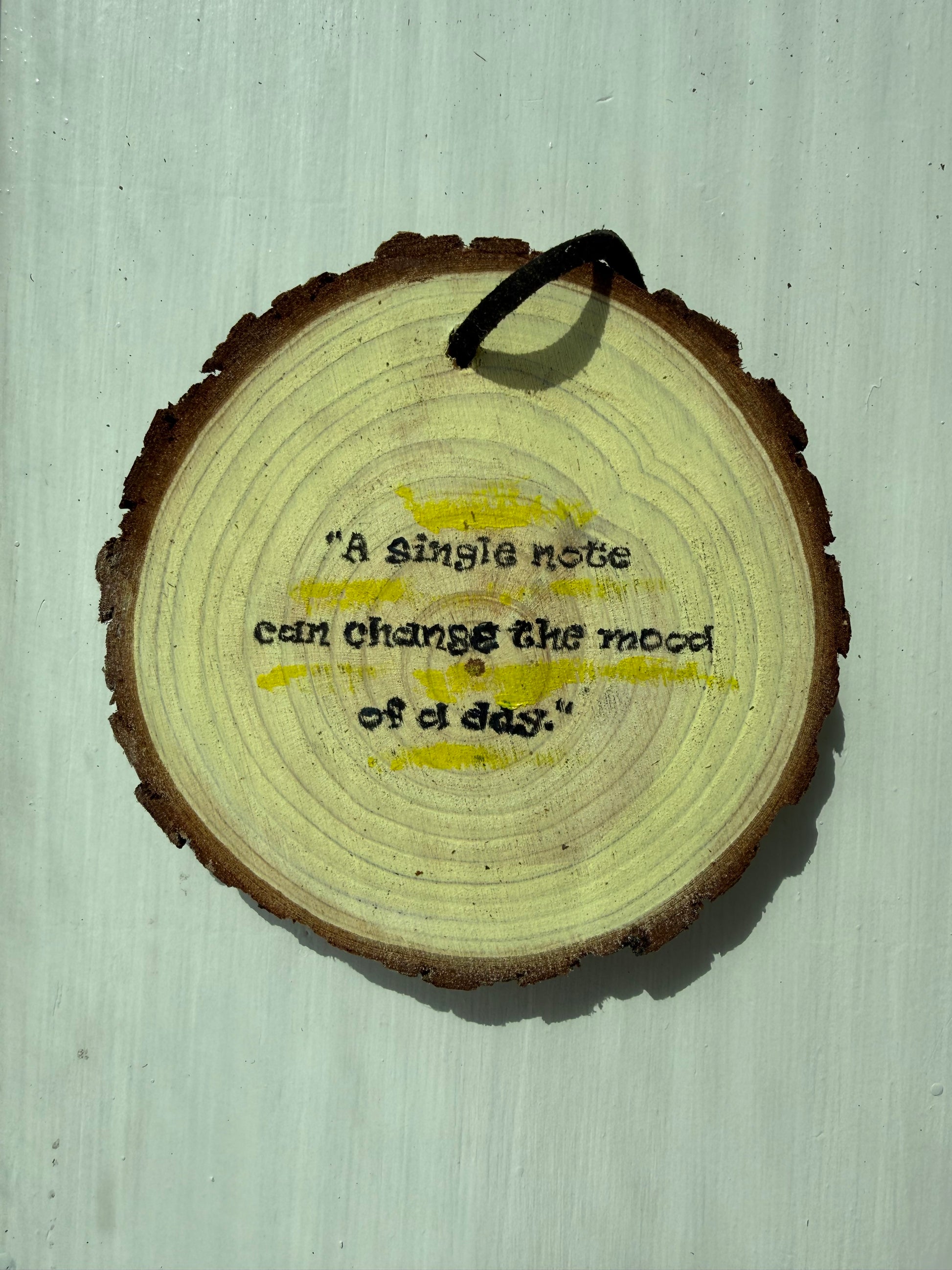 Wooden ornament that says "A single note can change the mood of a day."