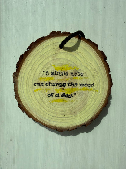 Wooden ornament that says "A single note can change the mood of a day."
