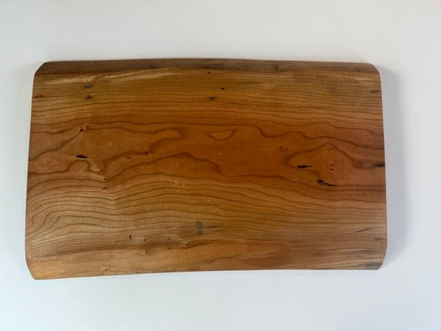 Wooden charcuterie board with live edge on a white background