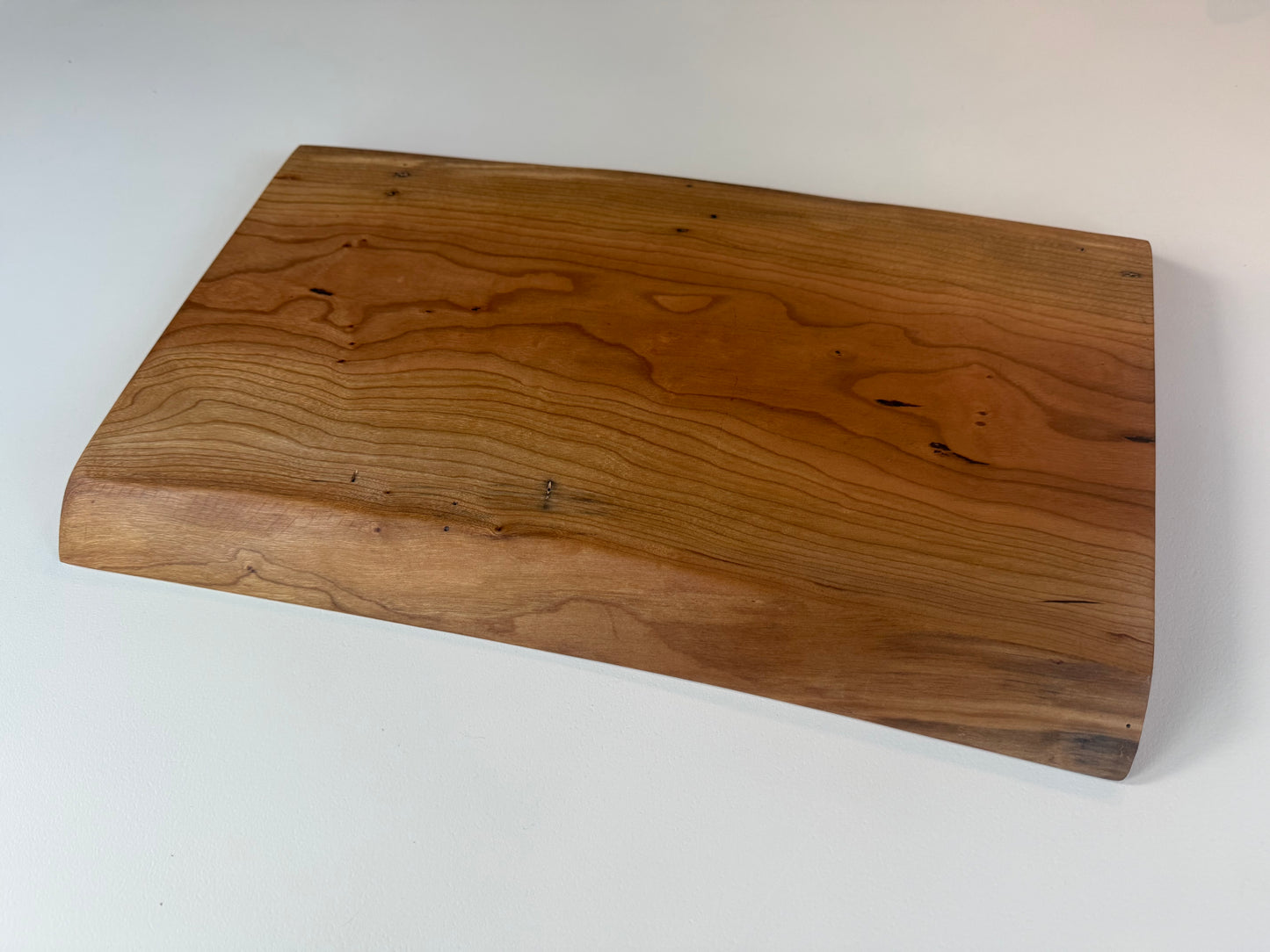 Wooden charcuterie board with live edge on a white background