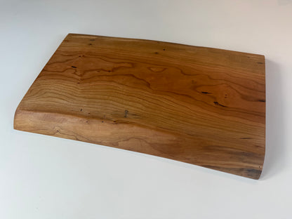 Wooden charcuterie board with live edge on a white background