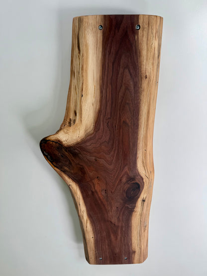 Wooden charcuterie board with a natural edge on a white background