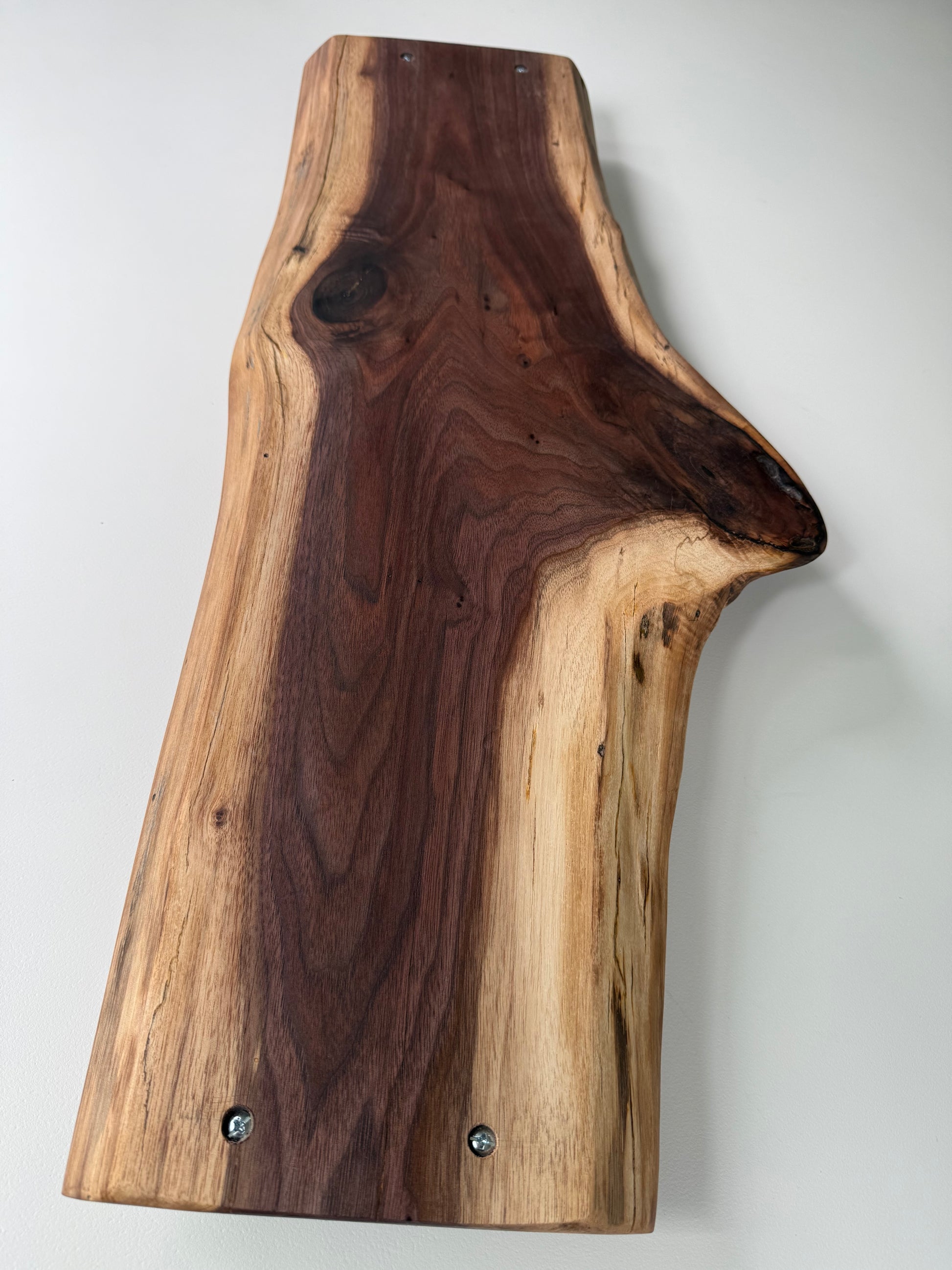 Wooden charcuterie board with a natural edge on a white background