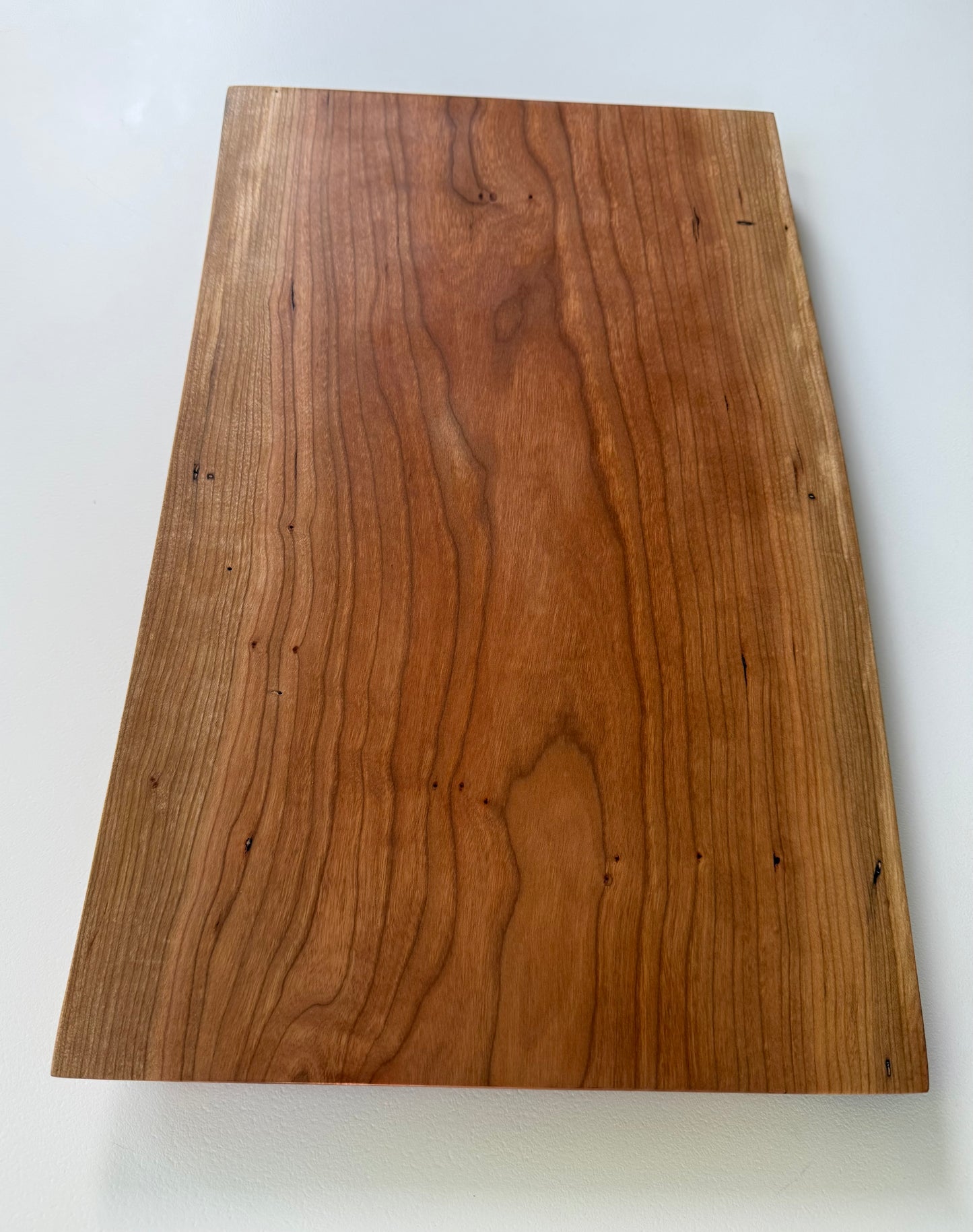 Wooden charcuterie board with live edge on a white background