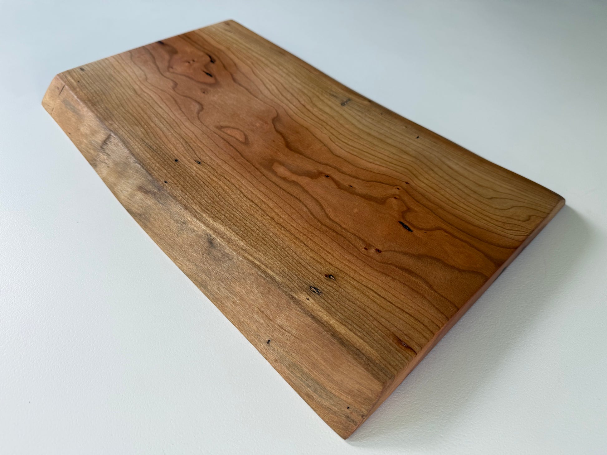 Wooden charcuterie board with live edge on a white background