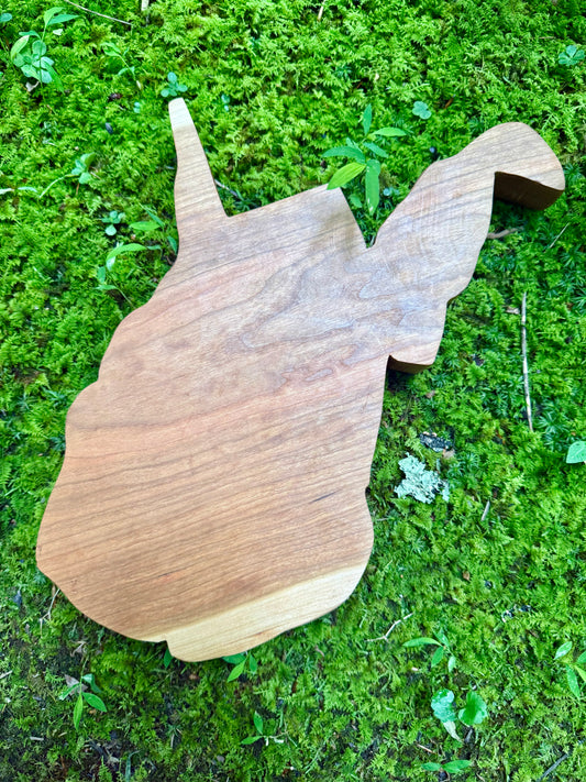Wooden West Virginia shaped charcuterie board on a green mossy background