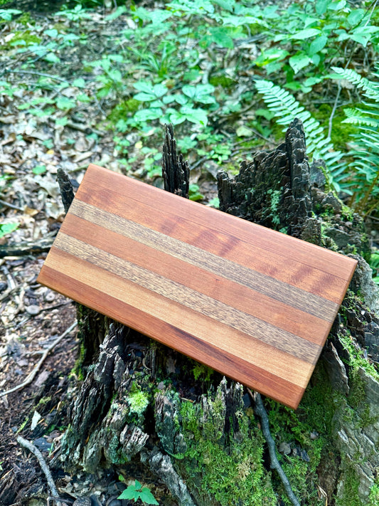 Wooden cutting board with striped pattern on a tree stump in a forest setting