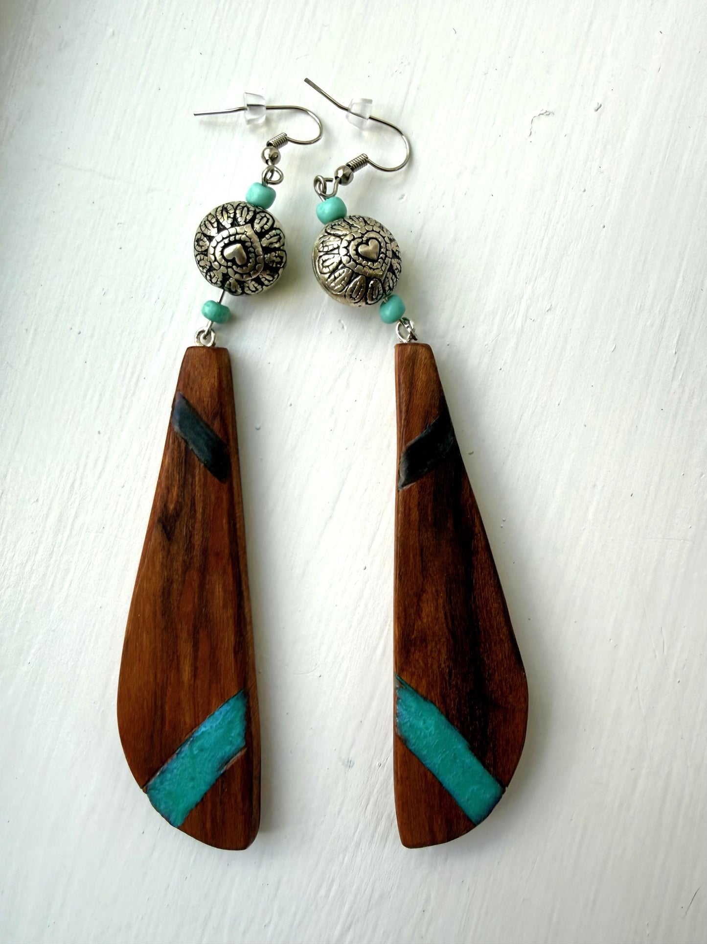 Wooden earrings with turquoise accents and silver beads on a white background