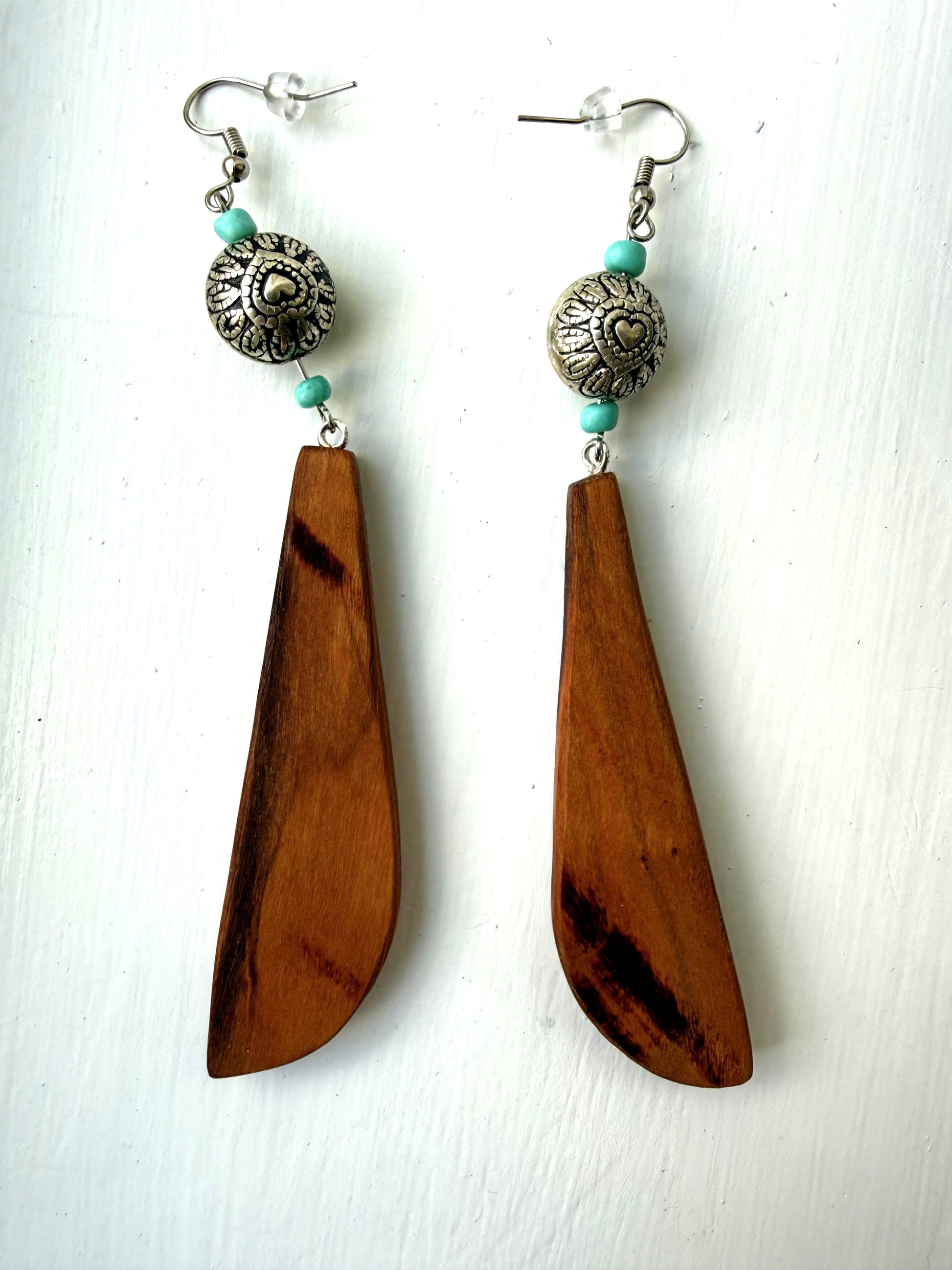 Wooden earrings with turquoise accents and silver beads on a white background