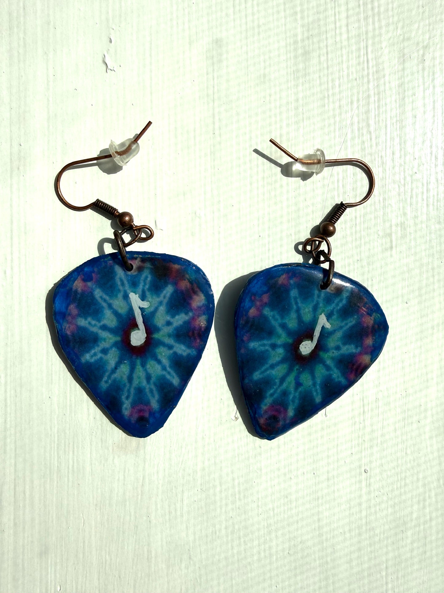 Blue tie-dye earrings with a music note design on a white background