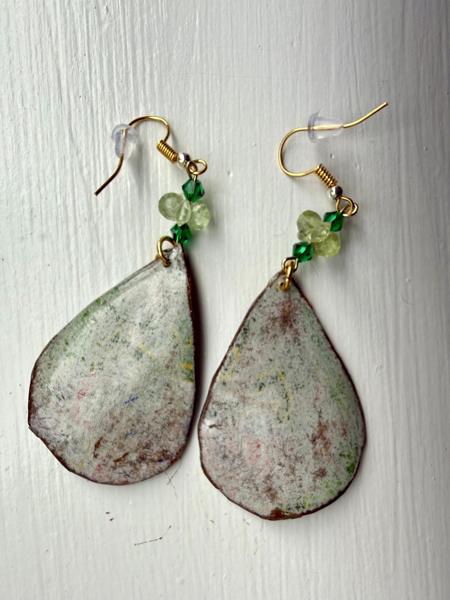 Teardrop-shaped earrings with green beads on a white background