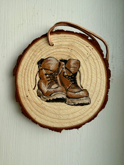 Wooden ornament with a design of hiking boots on a plain background