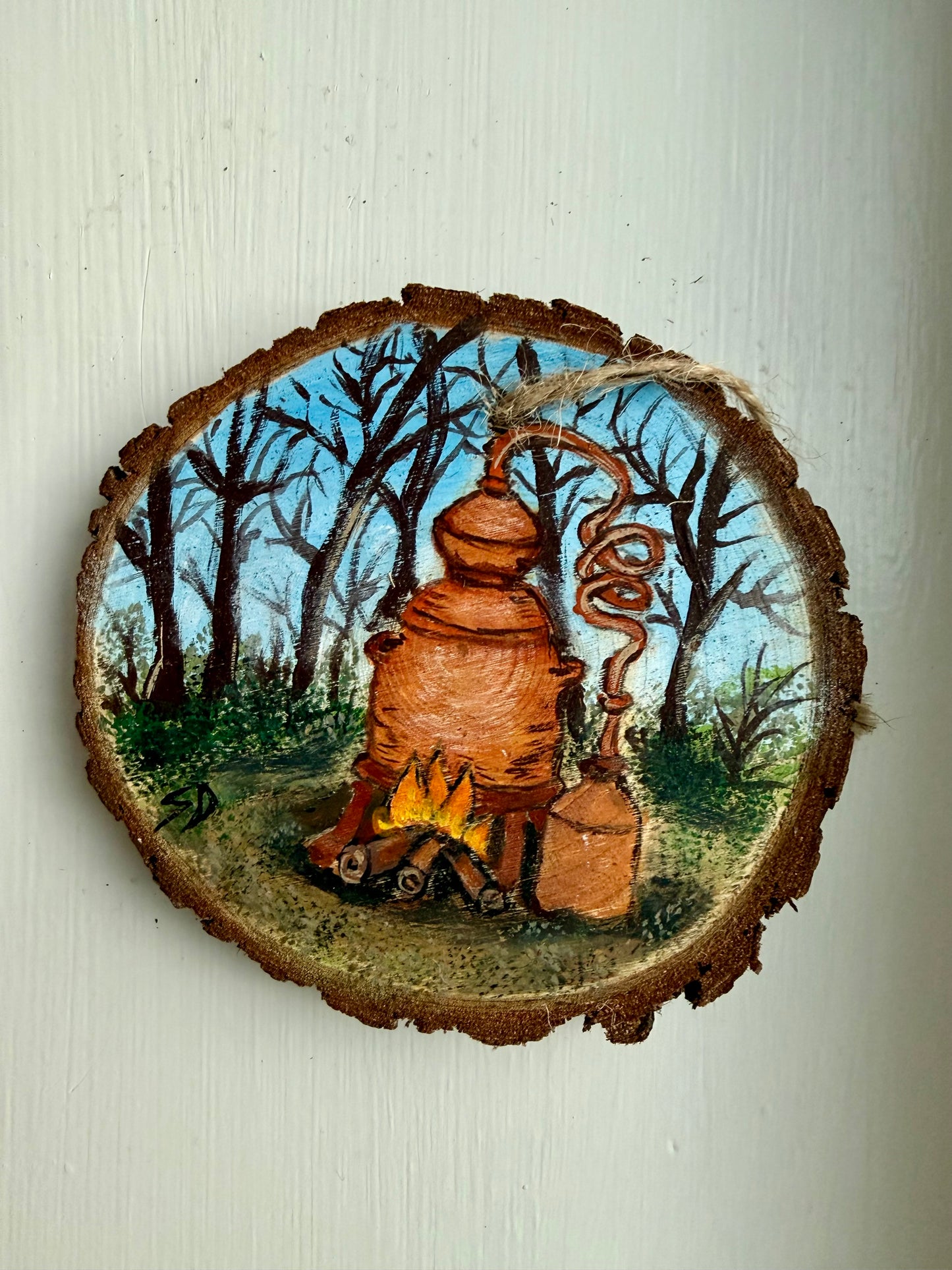 Wooden ornament featuring a moonshine still in a forest