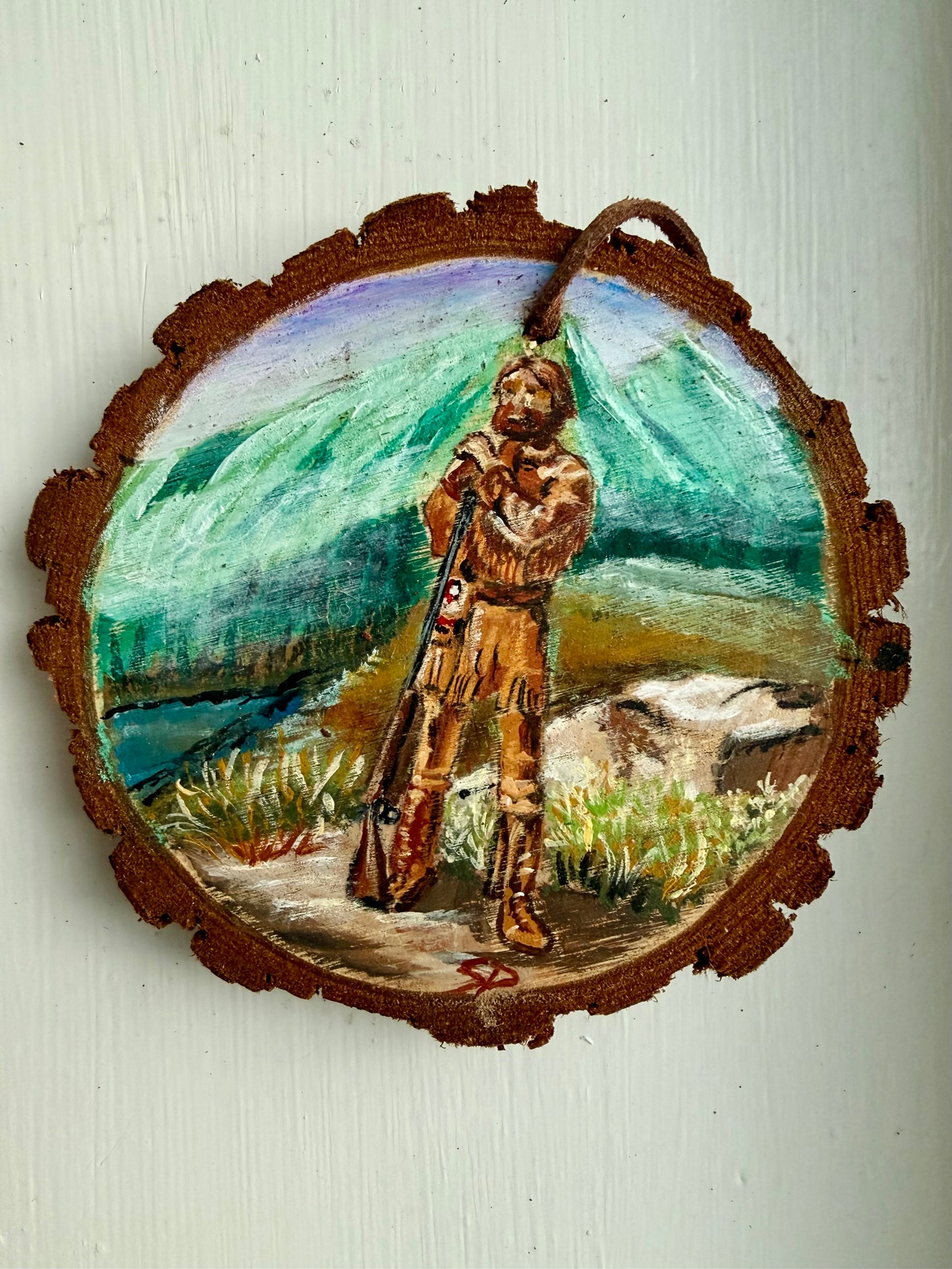 Wooden ornament featuring a mountain man design with a mountain landscape in the background