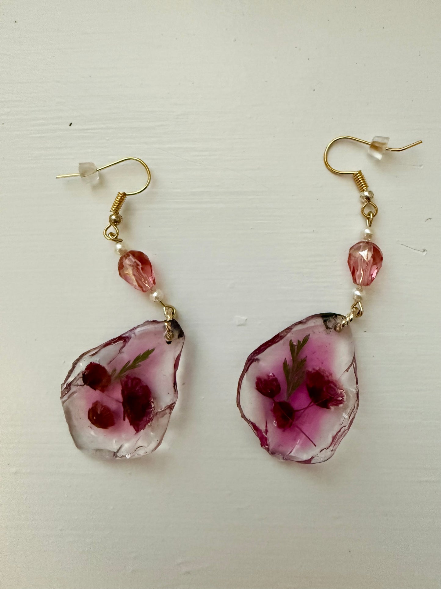 Teardrop earrings with dried flowers encased inside, displayed on a white background