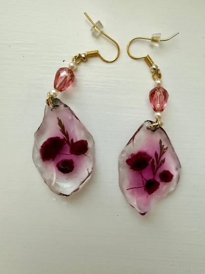 Teardrop earrings with dried flowers encased inside, displayed on a white background