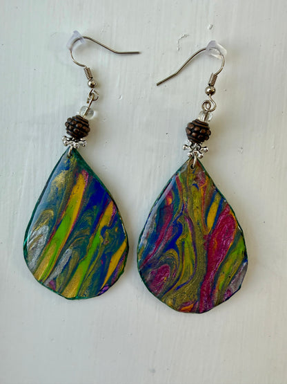 A pair of teardrop-shaped dangle earrings with colorful marbled paint designs in blue, green, yellow, pink, and white, hanging on silver coated metal hooks.