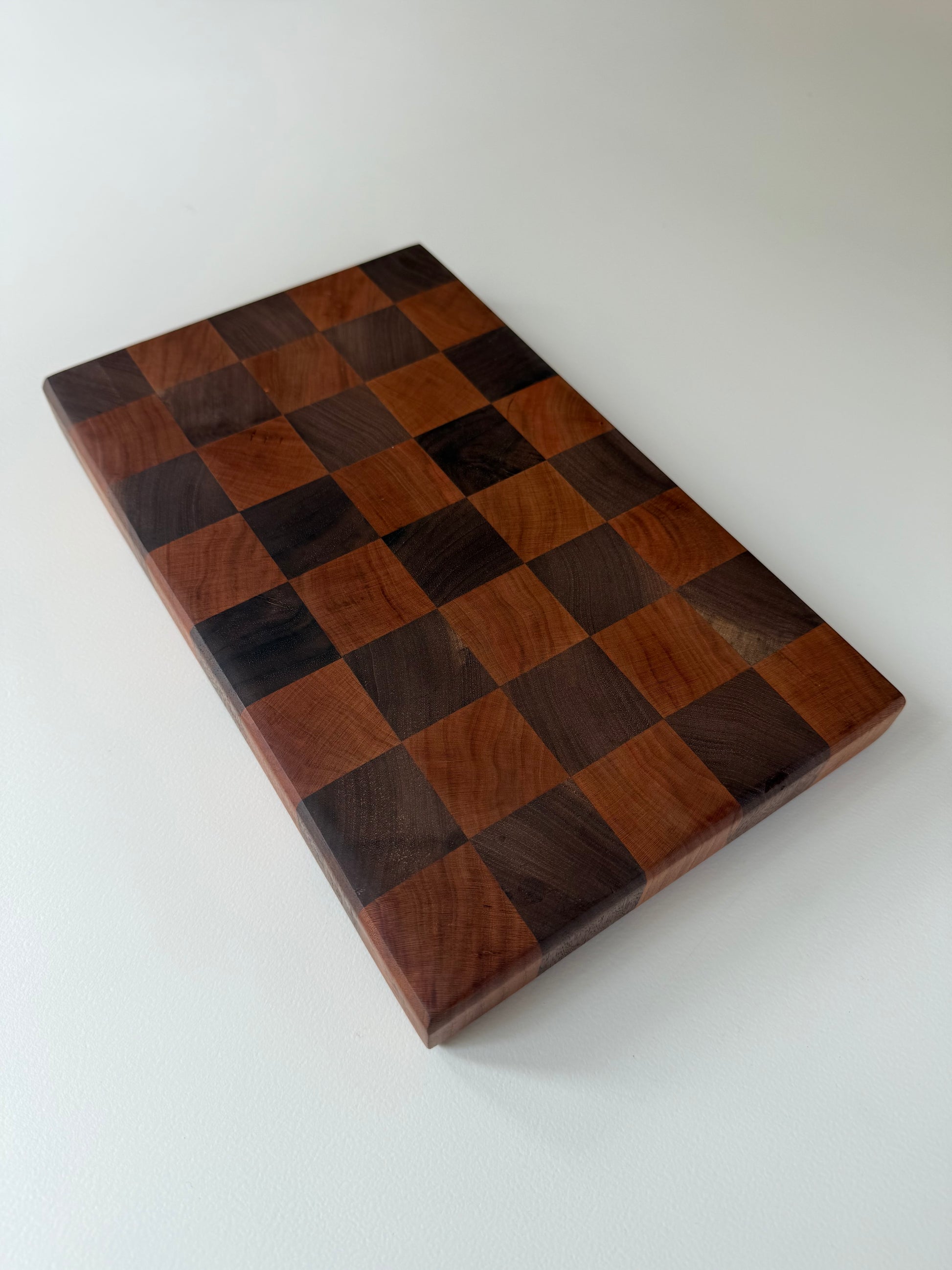 Square cutting board with a checkered cherry and walnut wood design